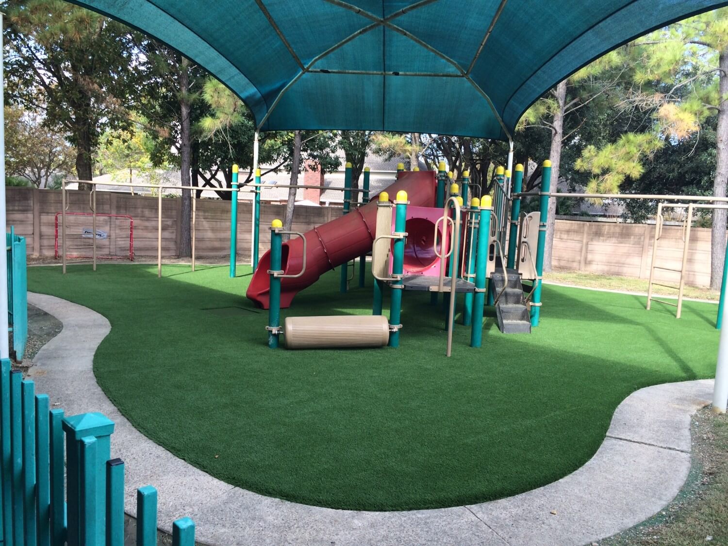 red slide installed on artificial playground grass