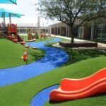 Orange slide installed on artificial playground grass