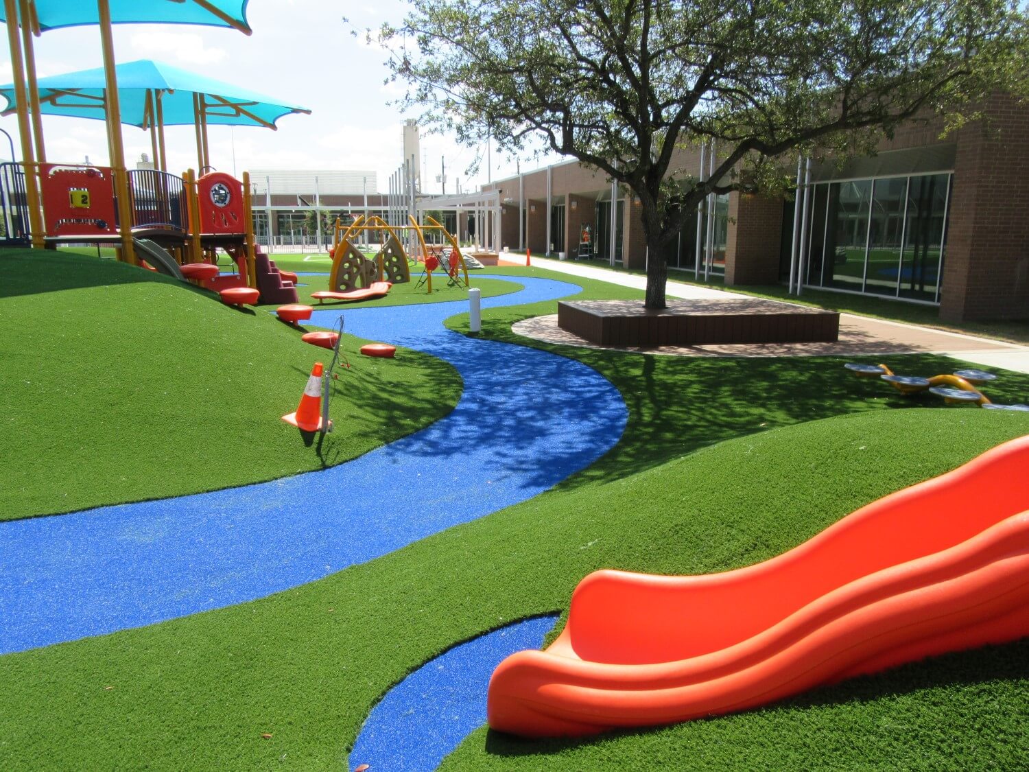 Orange slide installed on artificial playground grass