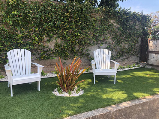 Artificial grass seating area with white chairs