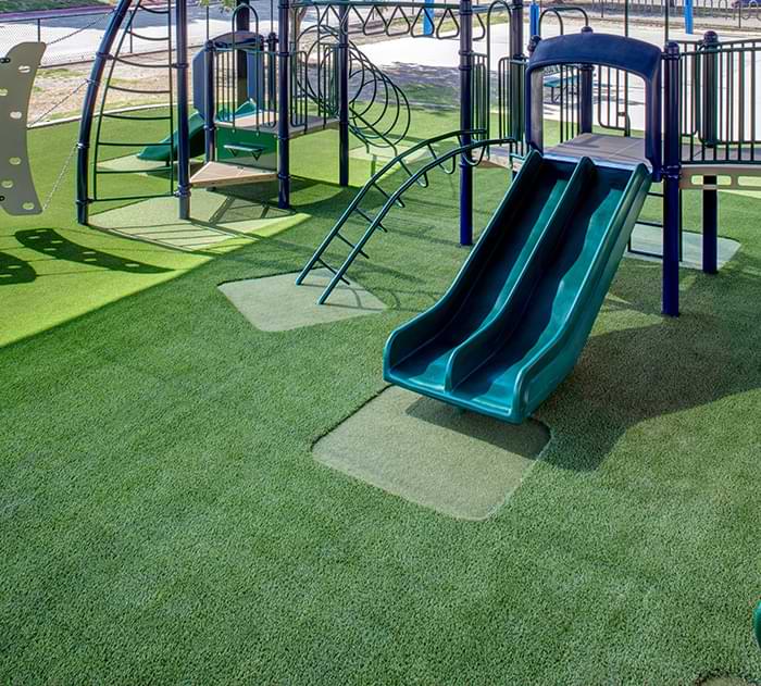 Green slide installed on commercial artificial playground grass from SYNLawn