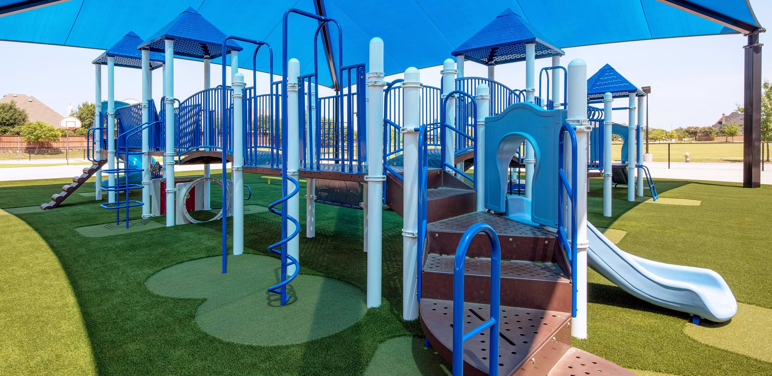 Blue jungle gym installed on artificial playground grass from SYNLawn